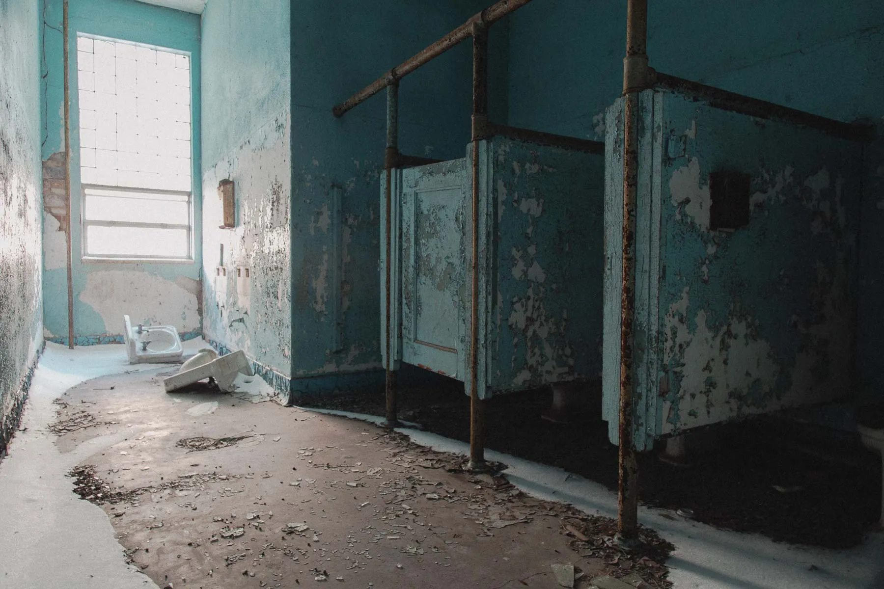 Blue tiled bathroom stalls inside Ayrshire Consolidated School