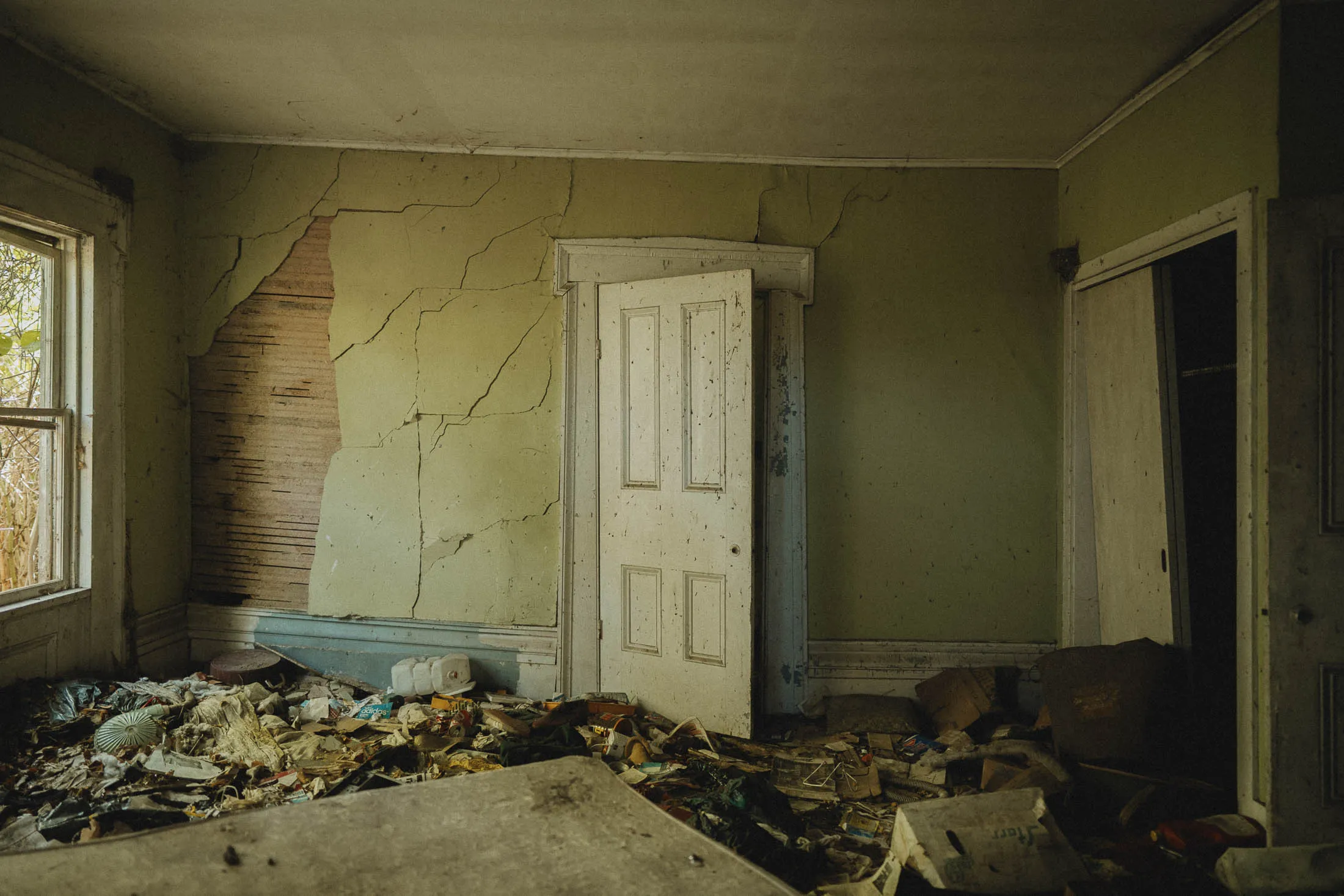 Living Room with four-panel door and Greek Revival molding, abandoned Cadillac House