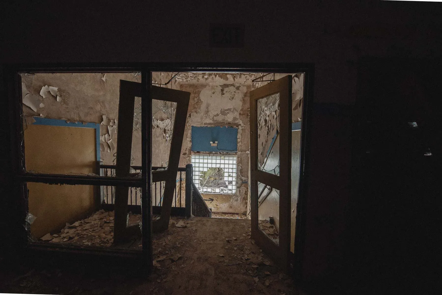 Broken doors hanging open in a corridor of the abandoned Columbus School