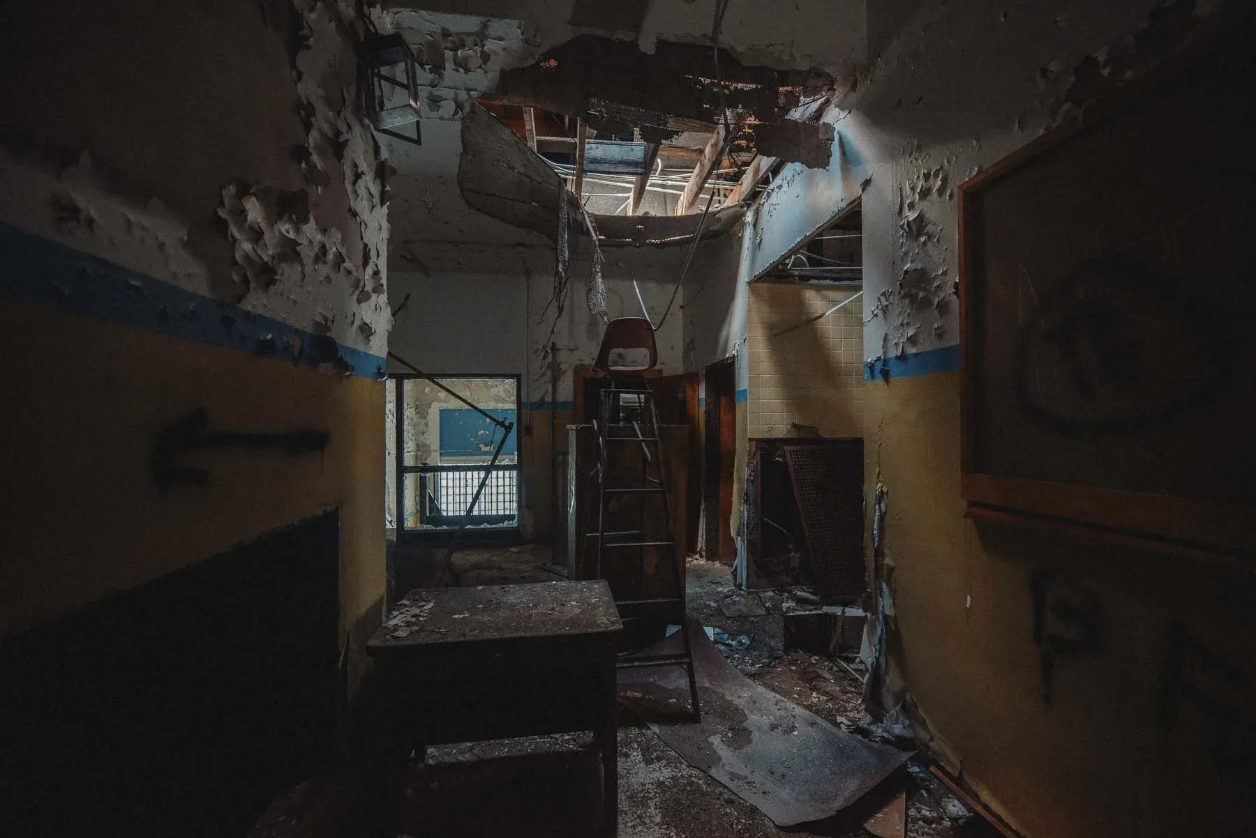 Hallway with a ladder and chair inside the abandoned Columbus School