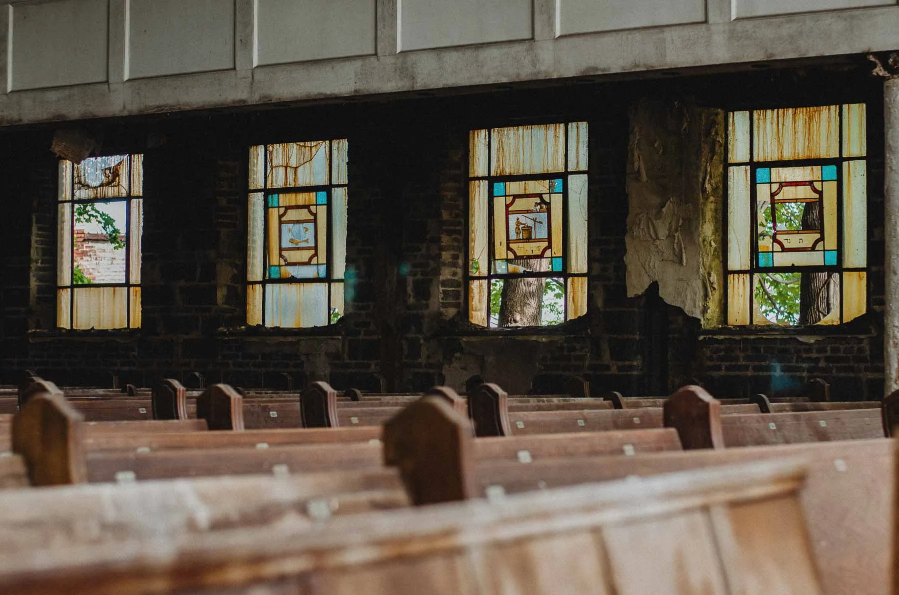 Stained glass windows filtering light over the north aisle pews