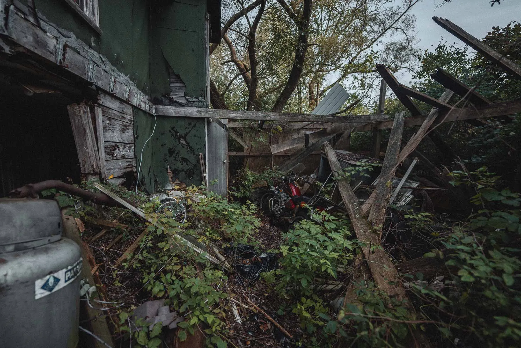 Entry door and Honda CX500 Custom inside the collapsed lean-to at the abandoned Dog House barndominium in Tioga County NY