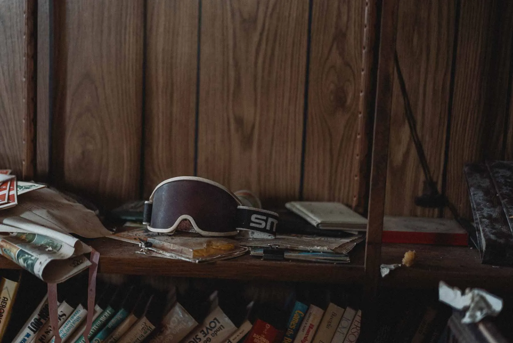 1980s Smith snowboarding goggles on a bookshelf inside the abandoned barndominium
