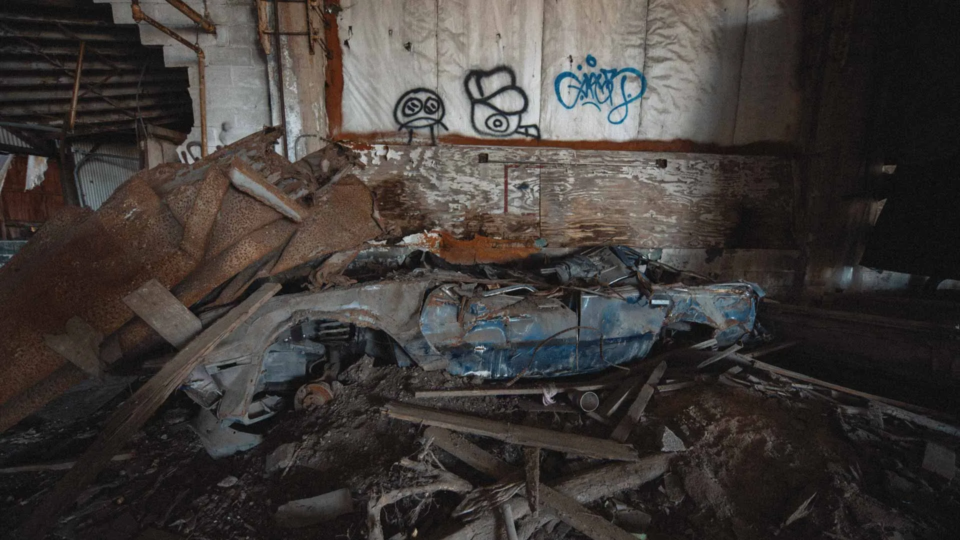 Crushed blue sedan surrounded by debris inside the D.W. Winkelman Co. warehouse