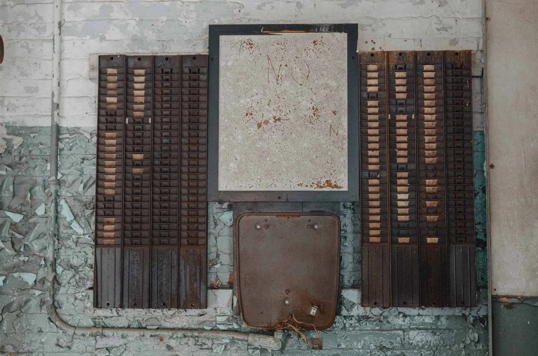 Rusting time card punch clock mounted to a brick column in the Fair Play Factory