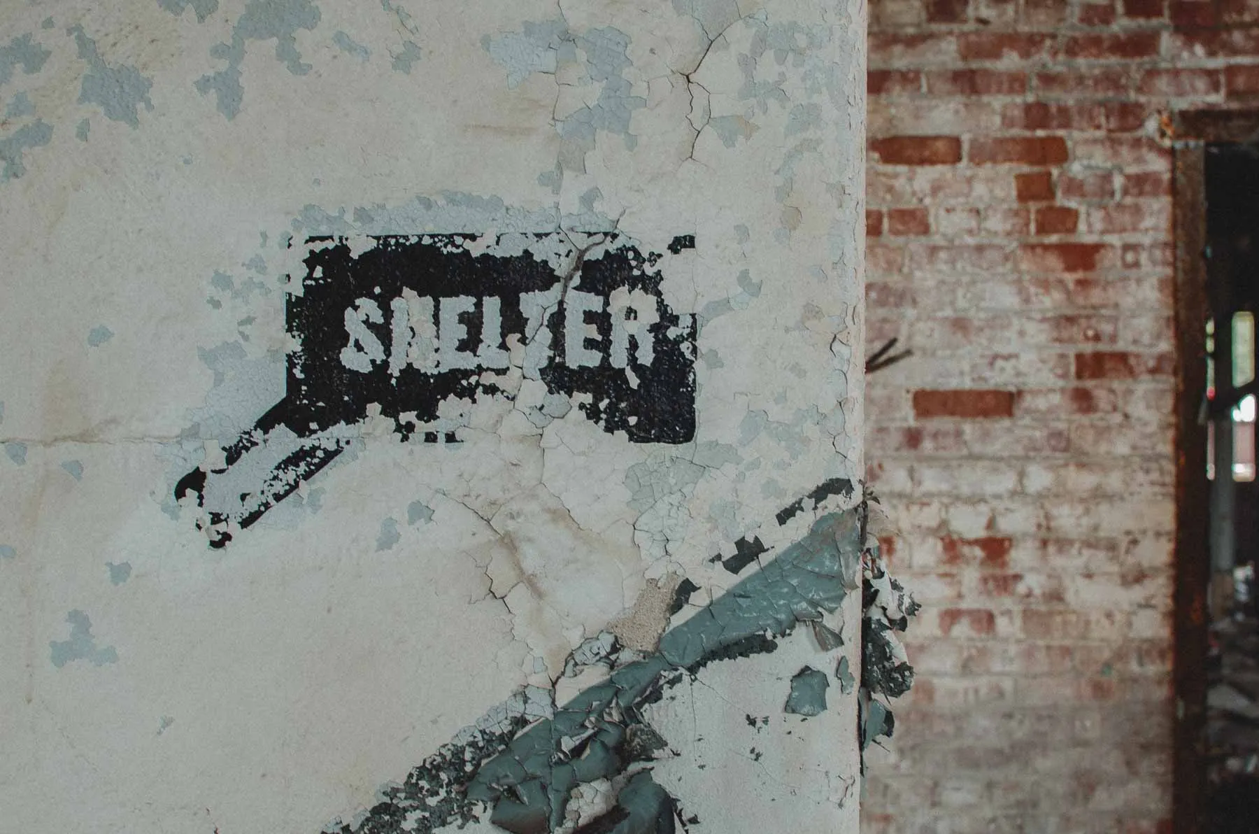 Hand-painted fallout shelter sign on a yellow column within the Fair Play Factory