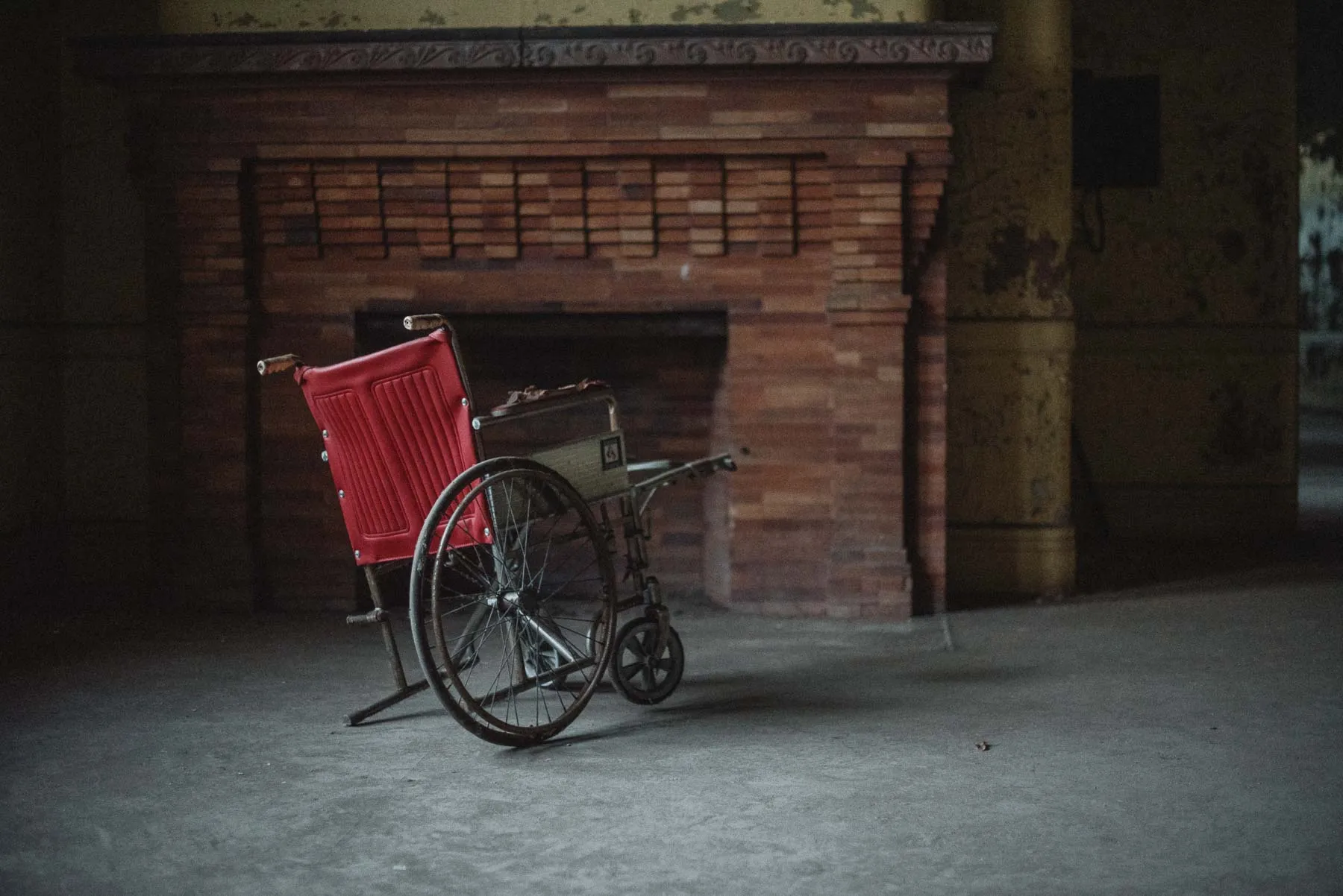 Red wheelchair beside a brick hearth inside the Richardson Olmsted Complex