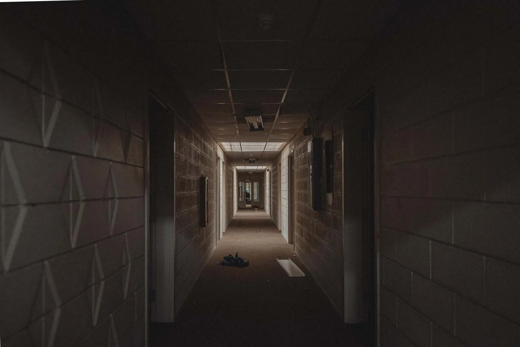 Cinderblock hallway with open doors inside the abandoned Vista Heights Inn